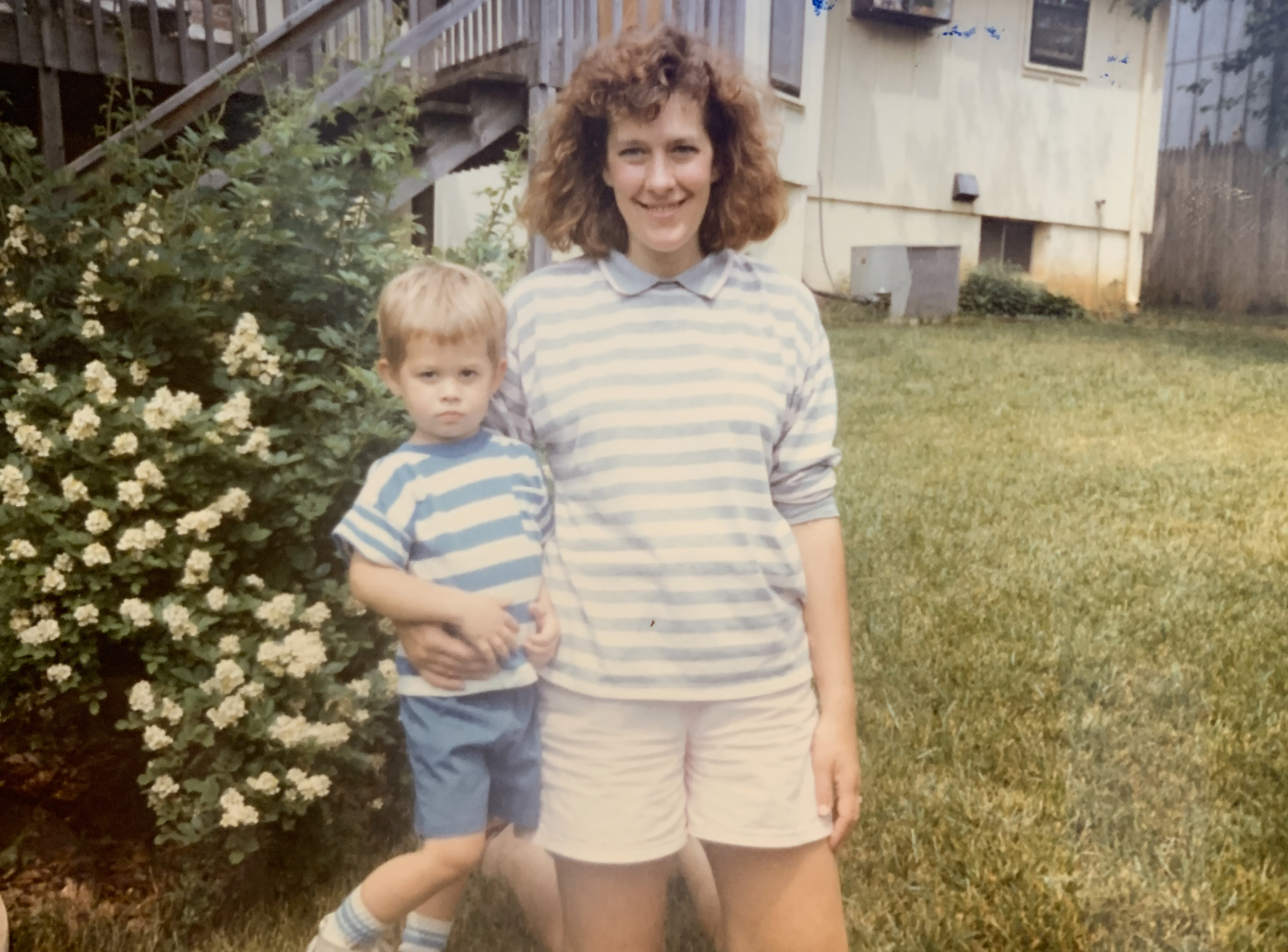 A family photo from the late 1980s showing a mother and young child in their backyard